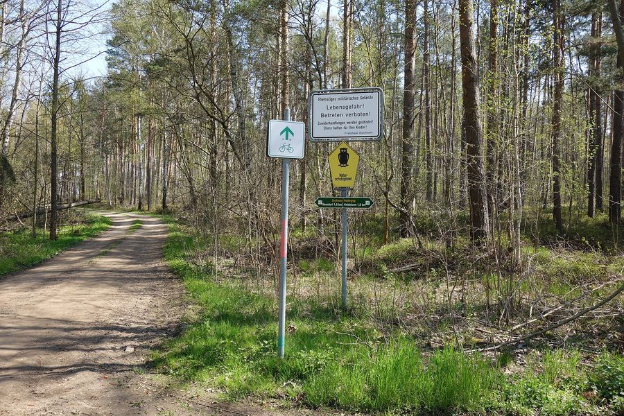 Wegweiser und Hinweisschild an einem Waldweg